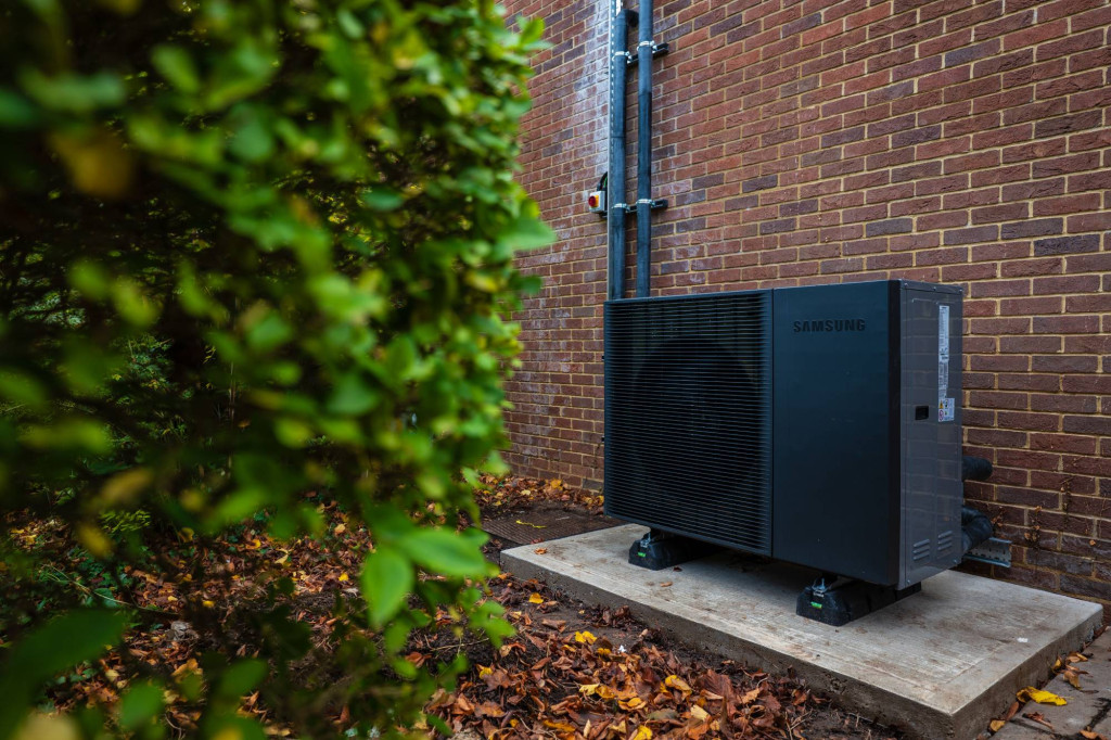 Air source heat pump on a concrete base beside the Estates office