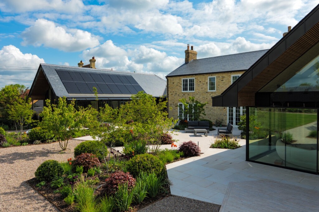 Stone farmhouse in Cambridgeshire with roof-mounted solar panels and a landscaped garden