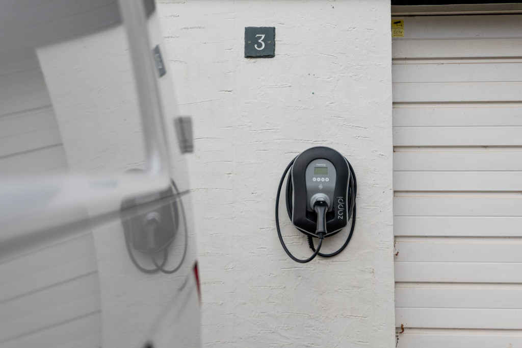 Wall-mounted EV charger beside a garage in Hilton