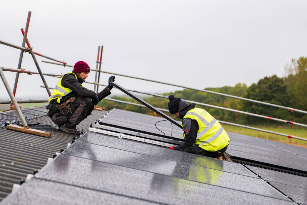Installers fitting solar panels on a barn roof at Sandon Manor